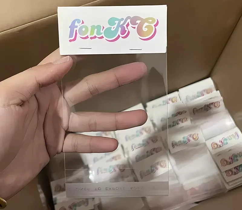 A clear poly bag with a fold-over header card held above a carton filled with assembled bag-and-header packs