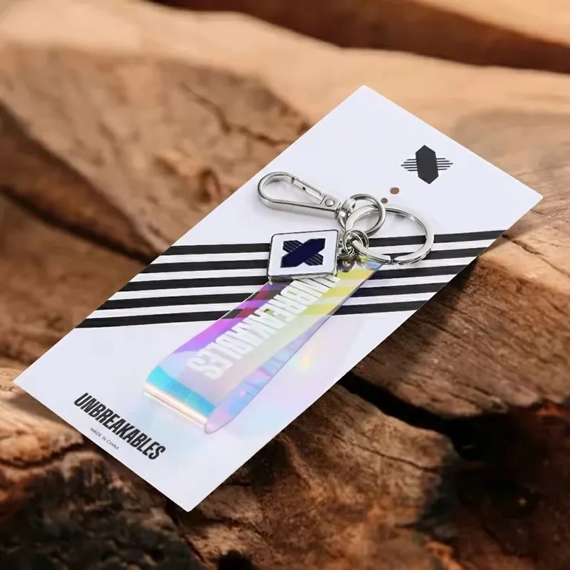 Holographic acrylic keychain mounted on a tall printed backing card, its clasp and keyring hanging through a hole at the top of the card