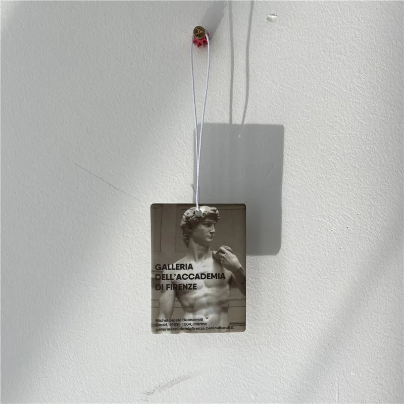 Clear acrylic keychain with a museum-tag design hanging against a plain wall