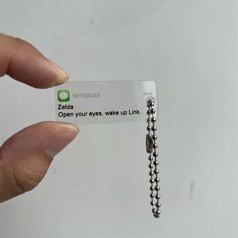 Clear acrylic keychain with printed message artwork held in a hand to show scale
