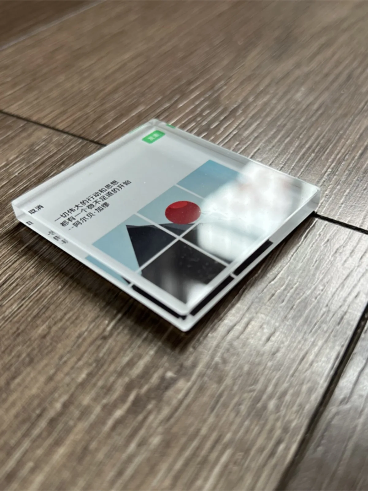 Clear acrylic fridge magnet seen at an angle on a wooden floor