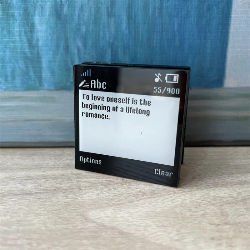 Black acrylic magnet card with a printed quote, standing against a wall