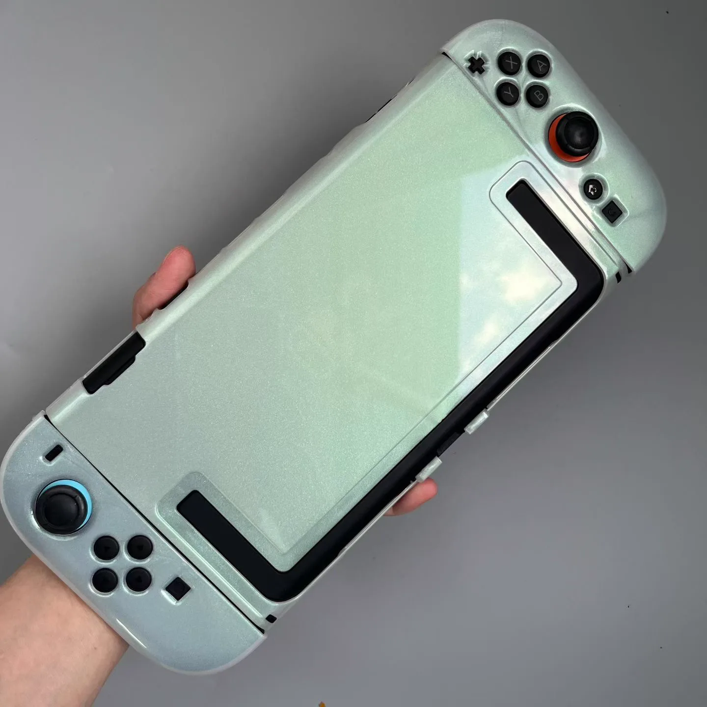 Pearlescent pale green protective shell fitted around a Nintendo Switch 2 console and controls