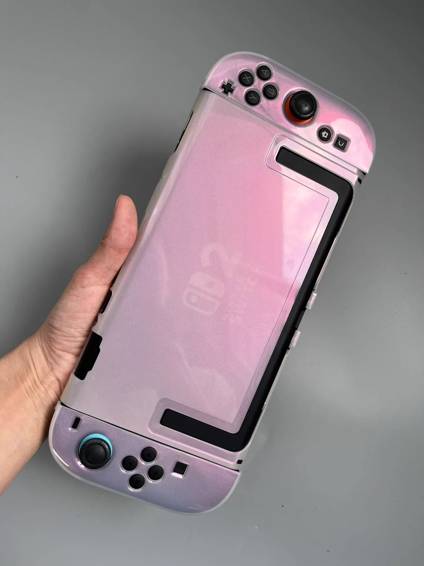 Pearlescent pink protective shell fitted to a Nintendo Switch 2 console held in one hand