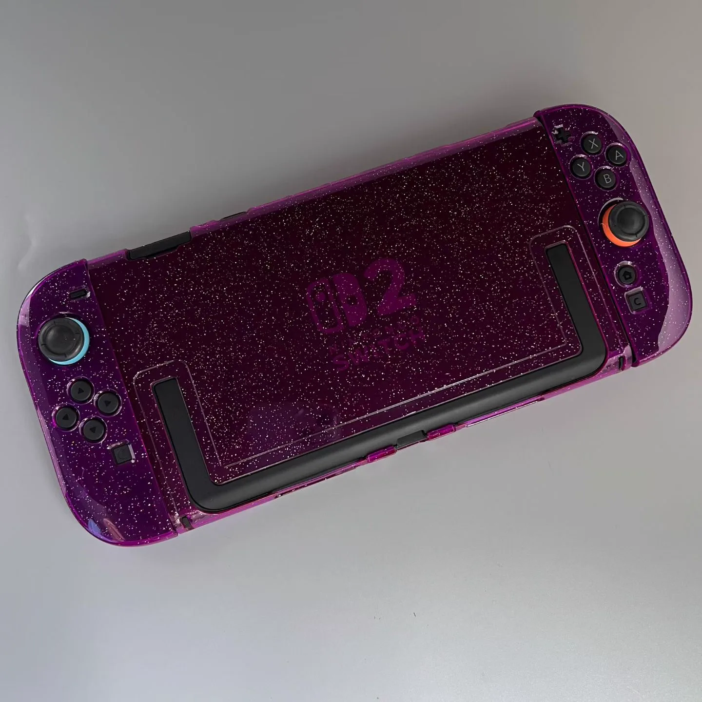 Purple glitter protective shell fitted around a Nintendo Switch 2 console and Joy-Con controllers