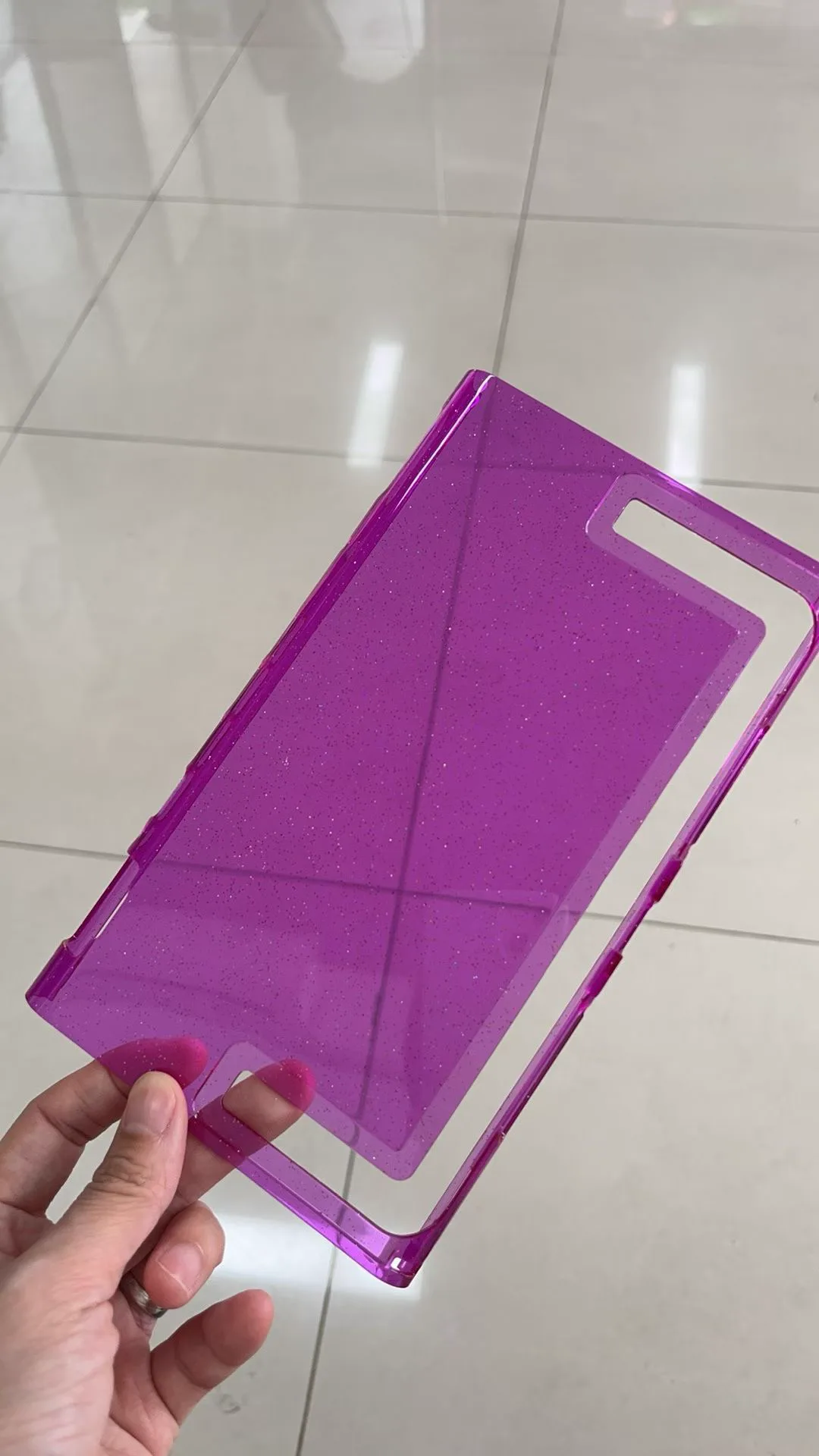 Purple-tinted transparent Nintendo Switch 2 back-shell sample held in one hand