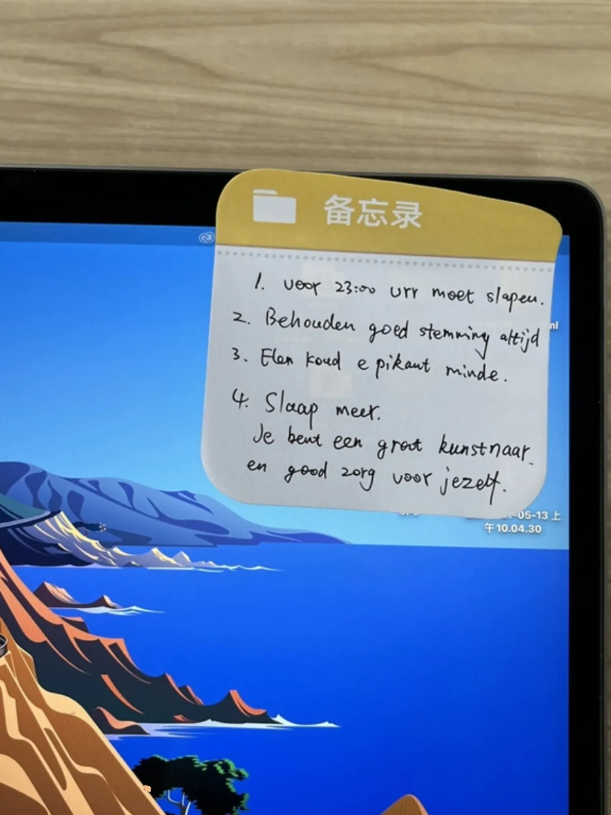 Sticky note with handwriting stuck to a tablet screen above a mountain wallpaper